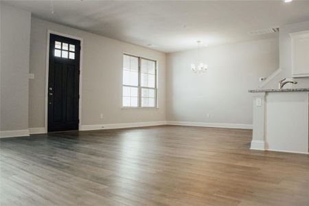 Unfurnished living room featuring a notable chandelier, light wood-type flooring, and sink