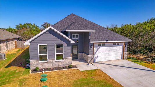 View of front of home featuring a front lawn, central air condition unit, and a garage