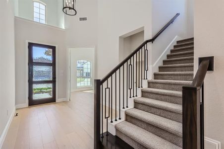 Entrance foyer with an inviting chandelier, light wood-type flooring, and a high ceiling