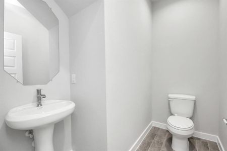 Sophisticated half bathroom adorned with contemporary finishes. The elegant 5-panel door welcomes you to a space where style meets functionality. Notice the sleek hardware accents that add a touch of modern charm. The vanity boasts light-colored countertops, beautifully complemented by a tasteful vanity light, creating a well-lit and inviting atmosphere. Sample photo of completed home with similar floor plan. As-built interior colors and selections may vary.