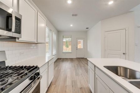 Kitchen with appliances with stainless steel finishes, light hardwood / wood-style floors, white cabinetry, sink, and decorative backsplash