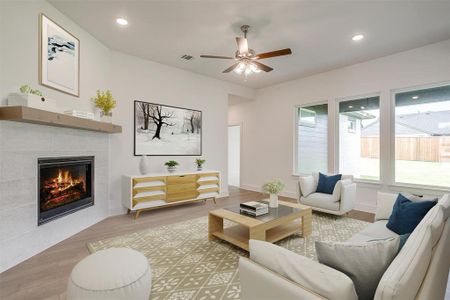 Living room with ceiling fan, a tiled fireplace, and wood-type flooring