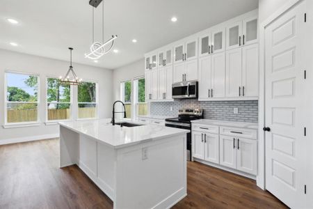 Kitchen featuring stainless steel appliances, white cabinetry, sink, an island with sink, and dark wood-type flooring