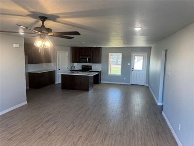 Kitchen featuring decorative backsplash, dark hardwood / wood-style floors, a kitchen island with sink, electric range, and dark brown cabinets