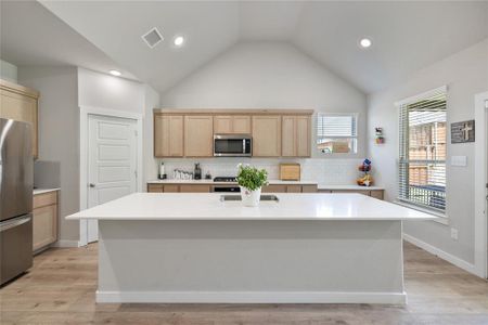 Kitchen with decorative backsplash, a center island, and appliances with stainless steel finishes