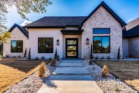 Exterior combines rough-cut stone & hand troweled stucco in neutral tones with black trim, featuring an impressive 61" x 81" Pivot steel & glass front door.