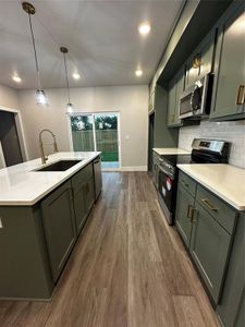 Kitchen with light stone counters, pendant lighting, sink, range, and dark hardwood / wood-style floors