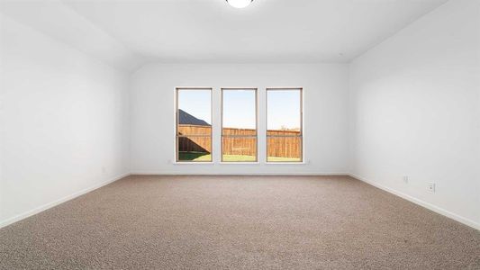 Carpeted spare room featuring vaulted ceiling