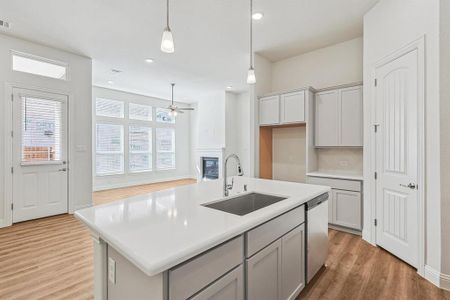 Kitchen featuring light hardwood / wood-style floors, an island with sink, pendant lighting, stainless steel dishwasher, and sink