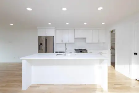 Kitchen featuring high quality fridge, a sink, white cabinetry, light countertops, and range with gas cooktop