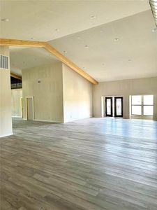 Spare room featuring beamed ceiling, high vaulted ceiling, and hardwood / wood-style flooring