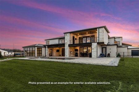 Back house at dusk with a patio area, a balcony, and a lawn