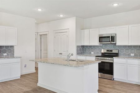 Kitchen with light wood-type flooring, sink, white cabinetry, decorative backsplash, and appliances with stainless steel finishes