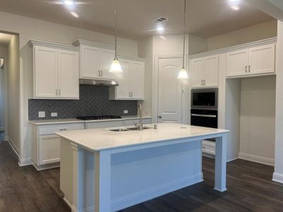 Kitchen with visible vents, built in microwave, under cabinet range hood, gas stovetop, and a sink