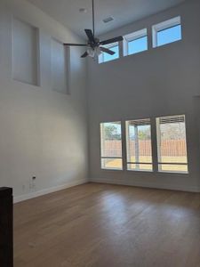 Spare room with a ceiling fan, a healthy amount of sunlight, visible vents, and wood finished floors