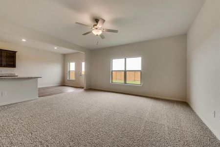 Unfurnished living room featuring ceiling fan and light colored carpet