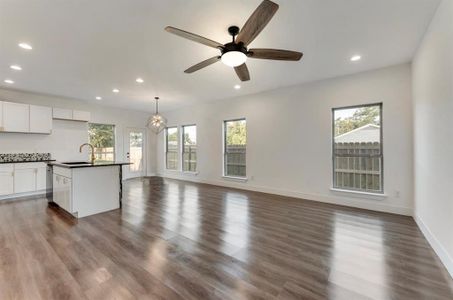 Unfurnished living room with dark hardwood / wood-style floors, sink, and ceiling fan