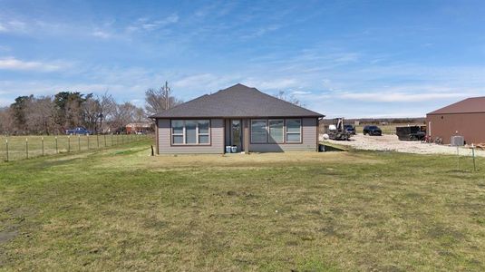 Back of house with a yard, a shingled roof, cooling unit, and fence