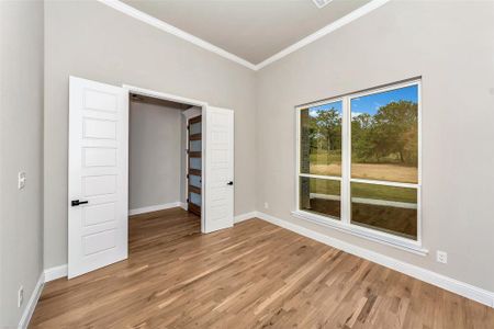 Unfurnished bedroom with light hardwood / wood-style flooring and crown molding