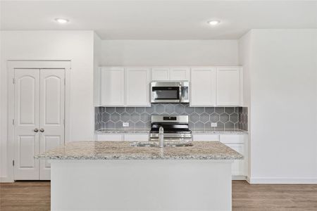 Kitchen with hardwood / wood-style floors, stainless steel appliances, and white cabinets