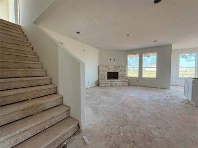 Unfurnished living room with a wealth of natural light, a fireplace, and stairs