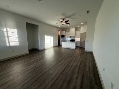 Unfurnished living room featuring ceiling fan, dark wood-type flooring, and sink