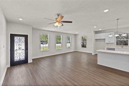 Unfurnished living room featuring a wealth of natural light, ceiling fan, dark hardwood / wood-style floors, and sink