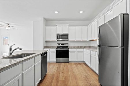 Chef ready kitchen with plenty of storage, granite countertops, designer white cabinetry, luxury vinyl plank flooring and a suite of energy-efficient Whirlpool appliances - including refrigerator with ice maker.