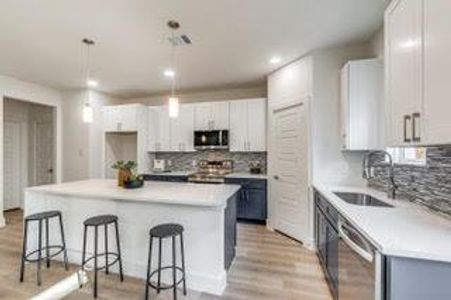 Kitchen with white cabinetry, light hardwood / wood-style flooring, tasteful backsplash, a center island, and appliances with stainless steel finishes