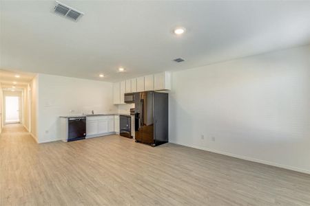 Kitchen featuring sink, light hardwood / wood-style floors, white cabinetry, and black appliances