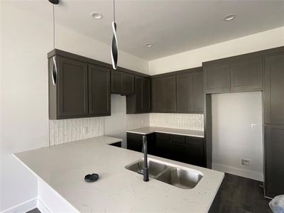 Kitchen with hardwood / wood-style floors, backsplash, sink, hanging light fixtures, and kitchen peninsula