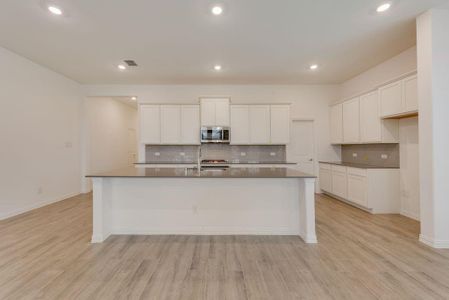 Kitchen featuring white cabinets, light hardwood / wood-style floors, and tasteful backsplash