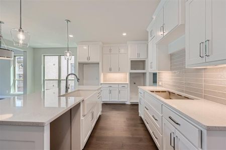 Kitchen featuring light stone countertops, tasteful backsplash, and an island with sink