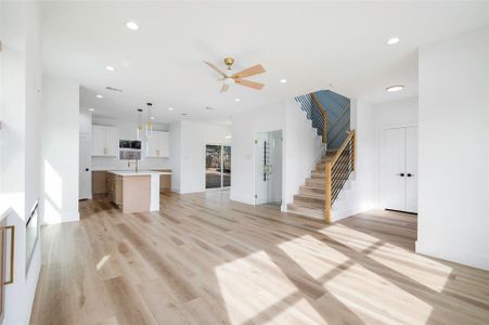 Unfurnished living room with ceiling fan, light wood-type flooring, and sink