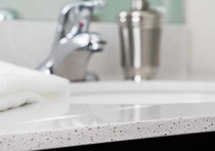 Sea Forest Beach Club model home bathroom with white travertine countertop, fresh towel, and chrome faucet and soap dispenser