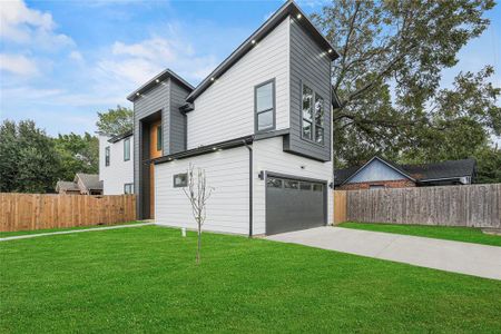 View of side of property featuring a garage and a lawn