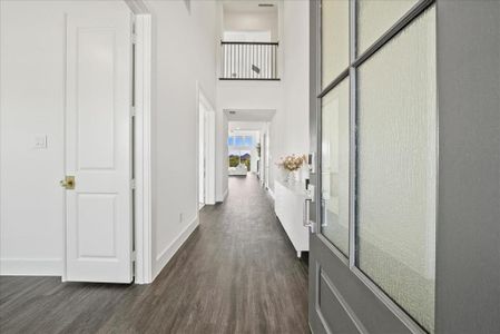 Corridor featuring dark wood-type flooring, a high ceiling, and baseboards