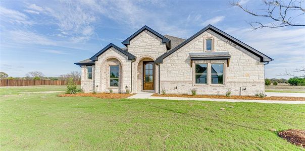 French country inspired facade with a front lawn