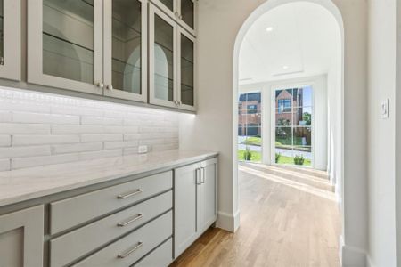 Bar featuring backsplash, light stone countertops, light hardwood / wood flooring, and gray cabinets