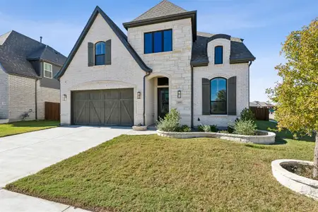 French provincial home featuring a garage and a front lawn