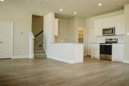 Kitchen featuring light stone counters, stainless steel appliances, light hardwood / wood-style floors, and white cabinets