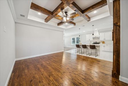 Living room featuring ceiling fan, hardwood / wood-style floors, beamed ceiling, and coffered ceiling