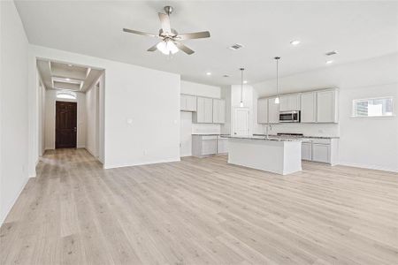 Unfurnished living room with ceiling fan, light wood-type flooring, and sink