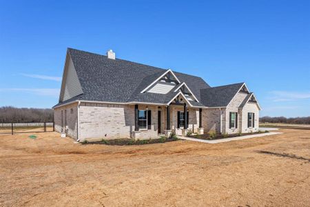 View of front of home featuring brick siding, a chimney, a porch, and roof with shingles