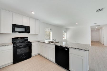 Kitchen with black appliances and white cabinets