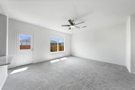 Living room with a wealth of natural light, ceiling fan, and light colored carpet