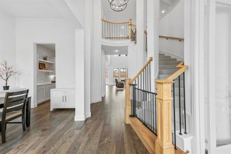 Grand entryway to stairs with natural wood finish and wrought iron spindles