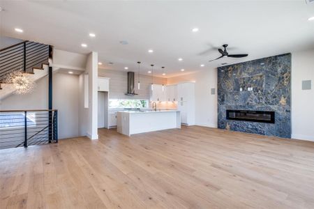 Unfurnished living room with ceiling fan, light hardwood / wood-style flooring, sink, and a large fireplace