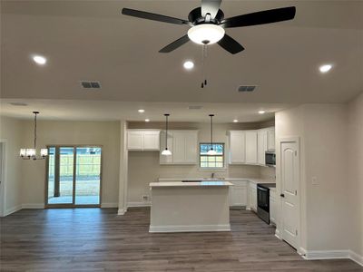 Kitchen with electric range, stainless steel microwave, sink, and large island.