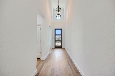 Hall with light hardwood / wood-style flooring and a high ceiling